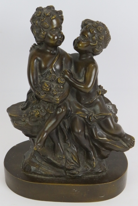 A small bronze figure of two young children sitting on a rock. Bearing signature Aug. Moreau (