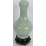 An antique Chinese celadon gourd vase with underglaze incised decoration standing on a later
