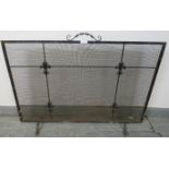 An Edwardian wrought iron and mesh freestanding fire screen, featuring fleur de lis mouldings, on