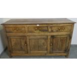 An 18th century oak and elm sideboard of three short drawers with brass swan neck handles, over