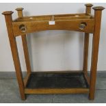 An Arts & Crafts light oak stick stand, with square finials and carved and pierced roundel