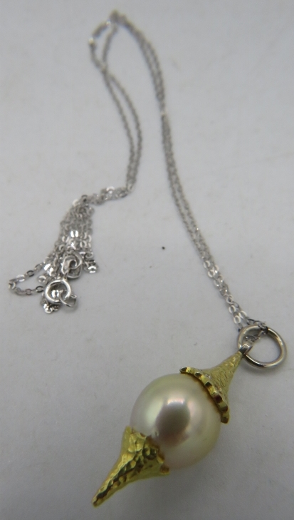 A bespoke Australian Golden Southsea pearl pendant set between planished yellow metal mounts. The