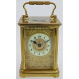 A 19th century gilt brass cased carriage clock with engraved gilt mask and enamelled dial ting.