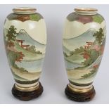 A pair of finely decorated Japanese Satsuma vases with traditional Mount Fuji scenes standing on