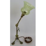 A brass Arts & Crafts desk lamp with adjustable arm, standing on lion paw feet and with a green