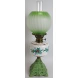 An early 20th century continental oil lamp with cast iron base, hand decorated Holly pattern