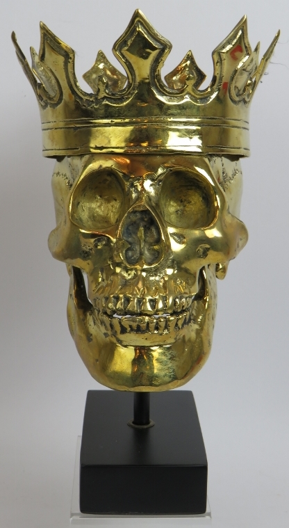 A contemporary polished bronze model of a human skull wearing a crown mounted on a bespoke plinth.