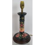 A Moorcroft pottery candlestick lamp base decorated with floral motifs mounted on a turned wood