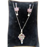 A white metal pendant set with a group of semi-precious stones including garnets, amethyst & topaz