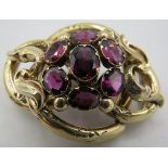 An antique unmarked yellow metal brooch/pendant set with a cluster of seven oval garnets. Centre