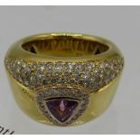 A heavy 18ct yellow gold ring set with centre pink trillion cut sapphire surrounded by bands of