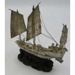 A Chinese white metal three sail junk on a wooden base, approx 4" x 4". Condition report: Good