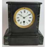 A small antique slate mantel clock with enamelled dial. Key and pendulum present. Height 23cm.