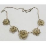 A Portuguese sterling silver necklace decorated with 5 graduated filigree roses, each joined by a