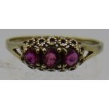 A 9ct yellow gold ring set with three rubies. The centre ruby approx 3mm, size L. Approx weight 1.