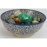 A blue and white Islamic pottery bowl containing a collection mainly semi precious stone eggs
