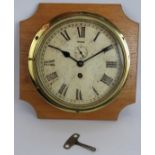 An early 20th century brass cased ships clock on oak mount. Key present. Dial 20cm diameter.