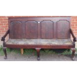 An 18th century oak settle, the backrest with fielded panels, joined with open-sided armrests, on