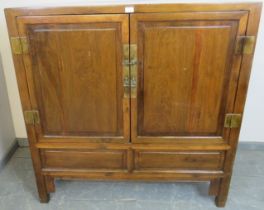 A vintage tropical hardwood Chinese wedding cabinet with brass fittings, the double doors opening