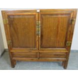 A vintage tropical hardwood Chinese wedding cabinet with brass fittings, the double doors opening