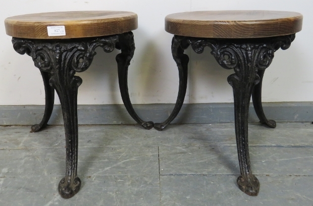 A pair of small medium oak stools, on splayed cast iron supports with acanthus leaf decoration.