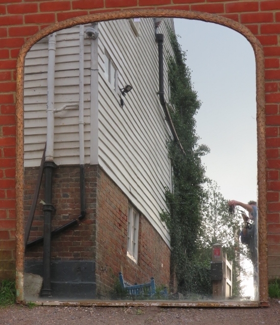 A very large 19th century arched overmantle mirror, retaining the original mercury glass plate, in a