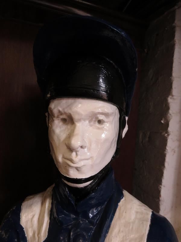 A life-size painted plaster figure of a jockey in racing colours, with riding crop, on a plinth - Image 5 of 5