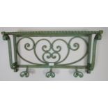 A vintage wrought iron wall hanging shelf painted green, featuring scrolled decoration, with three