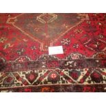 A mid 20th century Persian carpet. 3 repeat central motifs with stylised birds on a claret field.