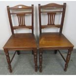 A pair of Edwardian hall chairs with pierced back splats, on tapering turned supports with side