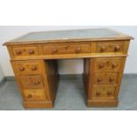 A late Victorian light oak pedestal desk of small proportions, housing an array of seven graduated