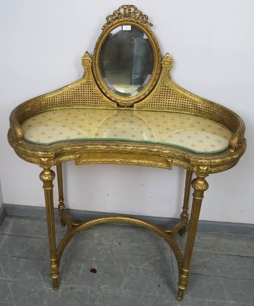 A vintage French giltwood dressing table, the double skin bergère gallery supporting a bevelled oval