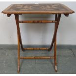 An Arts & Crafts walnut folding side table with pokerwork top depicting flora and fauna, on X