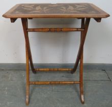 An Arts & Crafts walnut folding side table with pokerwork top depicting flora and fauna, on X