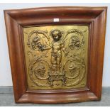 A Rococo embossed gilt brass panel depicting a cherub holding compasses and quill, mounted in an oak