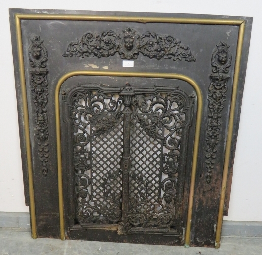 An antique cast iron and brass fireplace insert, the applied decoration depicting scrolling acanthus