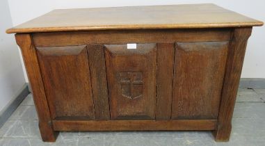 An Arts & Crafts oak coffer with fielded panels to all four sides and a relief carved shield to