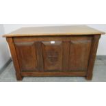 An Arts & Crafts oak coffer with fielded panels to all four sides and a relief carved shield to