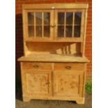 An antique stripped pine kitchen dresser, the glazed doors opening onto one loose shelf, over a