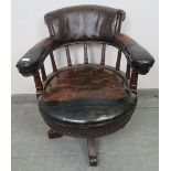An Edwardian mahogany captain’s swivel desk chair, upholstered in burgundy leather with brass studs,