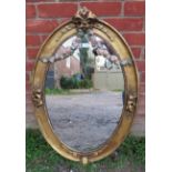 A 19th century oval wall mirror in an ornate gilt gesso frame featuring polychrome decoration in the