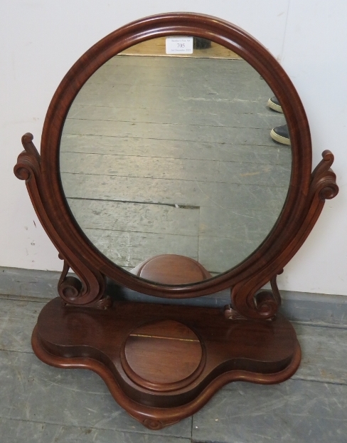 A Victorian mahogany oval swing vanity mirror, with scrolled and pierced uprights, on a shaped