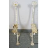 A pair of antique cast iron bench ends painted white, featuring acanthus leaf decoration.