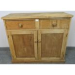 An antique stripped pine sideboard, housing two short drawers with turned wooden knob handles, above