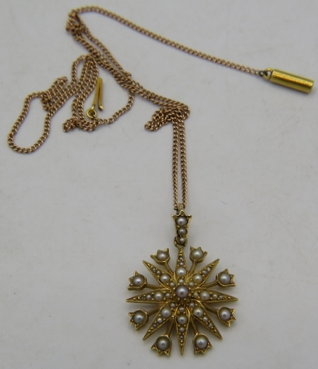 A yellow metal star shaped pendant set with seed pearls on a 15ct yellow gold fine link chain,