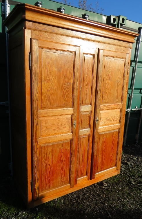 An antique French pitch pine armoire, the double doors with fielded panels, opening onto a hanging