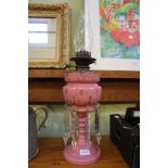 A LATE VICTORIAN PINK GLASS LUSTRE MOUNTED OIL LAMP 36.5cm high (to the top of the pink crown)