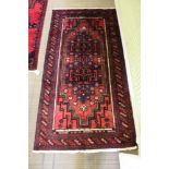 A woven woollen Meshed Belouch rug of typical geometric and stylised flower head design, 215cm x