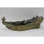 A late 19th century Eastern brass table stand in the form of a boat, with dragon figure head, 40cm