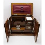 An Edwardian oak desk top stationery cabinet, hinged lid and two front doors open to reveal a fitted